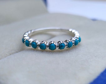 May include: A silver ring with a row of turquoise stones.