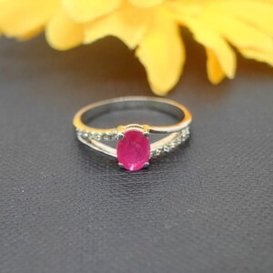 May include: A silver ring with a pink oval gemstone and small clear stones on the band.