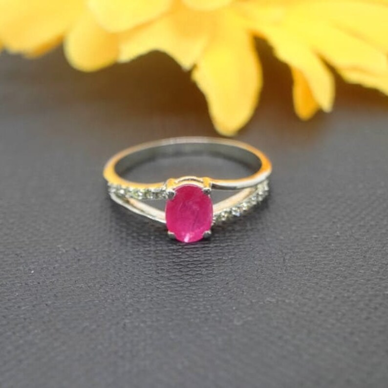 May include: A silver ring with a pink oval gemstone and small clear stones on the band.