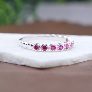 Könnte beinhalten: Ein silberner Ring mit einer Reihe kleiner rosa Edelsteine.