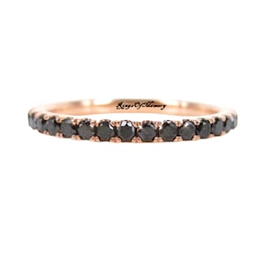 Può includere: Una sottile fascia in oro rosa con una fila di diamanti neri. La fascia è incisa con le parole "Rings of Memory".