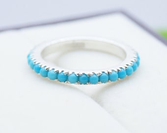 May include: A silver band ring with a row of turquoise stones.