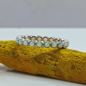 May include: A silver band ring with a row of white opal stones.