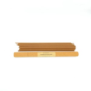 May include: A brown cardboard tube with a label that reads "Gem Generation Sandalwood Incense Sticks" and contains a bundle of brown incense sticks.