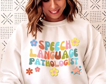 May include: White sweatshirt with the text "Speech Language Pathologist" in colorful retro font with flowers and stars.