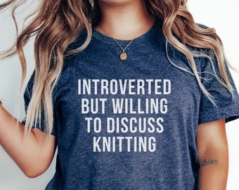 May include: A navy blue t-shirt with the text "Introverted but willing to discuss knitting" in white.