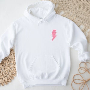 May include: White hoodie with a pink glitter lightning bolt graphic on the front.