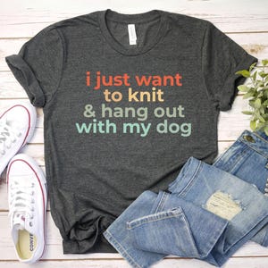 May include: A dark gray t-shirt with the text "i just want to knit & hang out with my dog" in a rainbow gradient.