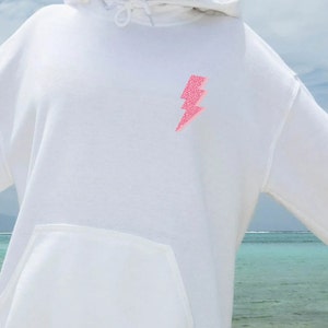 May include: White hoodie with a pink glitter lightning bolt design on the front.