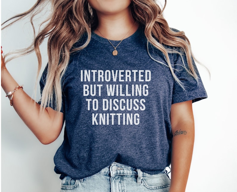 May include: A navy blue t-shirt with the text "Introverted but willing to discuss knitting" in white.