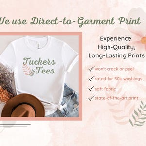 a white T-shirt with the text "Tuckers Tees" printed on it, along with a brown hat and some dried flowers. The image also includes text that describes the benefits of using Direct-to-Garment Print, such as a high-quality, long-lasting print that won't crack or peel, and a soft fabric state-of-the-art print.
