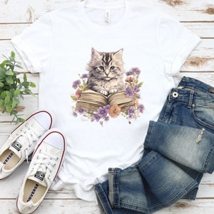 May include: White t-shirt with a graphic of a cat reading a book surrounded by flowers.