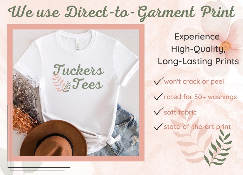 May include: White t-shirt with a green and pink floral design and the text "Tuckers Tees". The image shows the t-shirt on a table with a brown hat and blue jeans. The text "We use Direct-to-Garment Print" is at the top of the image. The text "Experience High-Quality, Long-Lasting Prints" is on the right side of the image. Below the text are four check marks with the following text: "won't crack or peel", "rated for 50+ washings", "soft fabric", and "state-of-the-art print".