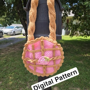 Puede incluir: Bolso de ganchillo hecho a mano con diseño de tarta rosa, con enrejado marrón y aplique de fresa. Tiene una correa trenzada marrón. El texto "Digital Pattern" es visible.