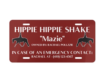 May include: A red personalized horse license plate with the text "HIPPIE HIPPIE SHAKE" and "Mazie" in white. The text "OWNED BY: RACHAEL POLLZZIE" and "IN CASE OF AN EMERGENCY CONTACT: RACHAEL AT - (419) 123-4567" is also included in white.