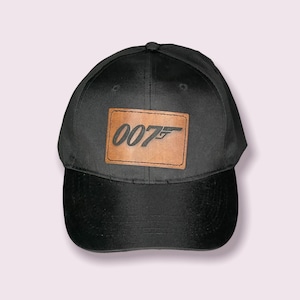 May include: A black baseball cap with a brown leather patch that says "007" in black lettering.