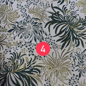 May include: A fabric featuring a repeating pattern of dark green and metallic gold chrysanthemum flowers on a light cream background. A circular red icon with the white number 4 is positioned in the center of the textile design.