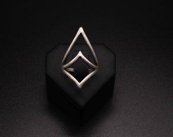 May include: A silver geometric ring with a diamond shape. The ring is displayed on a black velvet ring holder.