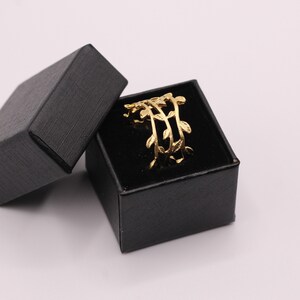 May include: A gold ring with a delicate leaf design, displayed in a black velvet ring box.