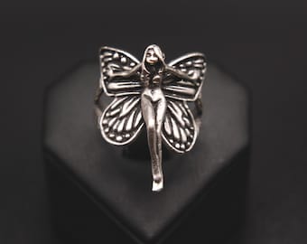 May include: A silver ring featuring a detailed fairy figure with wings shaped like a butterfly.