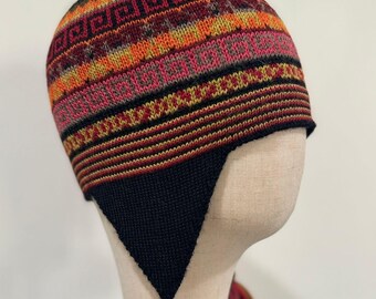 May include: A black knit hat with a colorful geometric pattern and two tassels. The hat has a pointed crown and ear flaps.