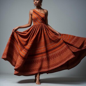 May include: A one-shoulder, floor-length dress with a rust-colored, patterned fabric. The dress has a fitted bodice and a flowing skirt.