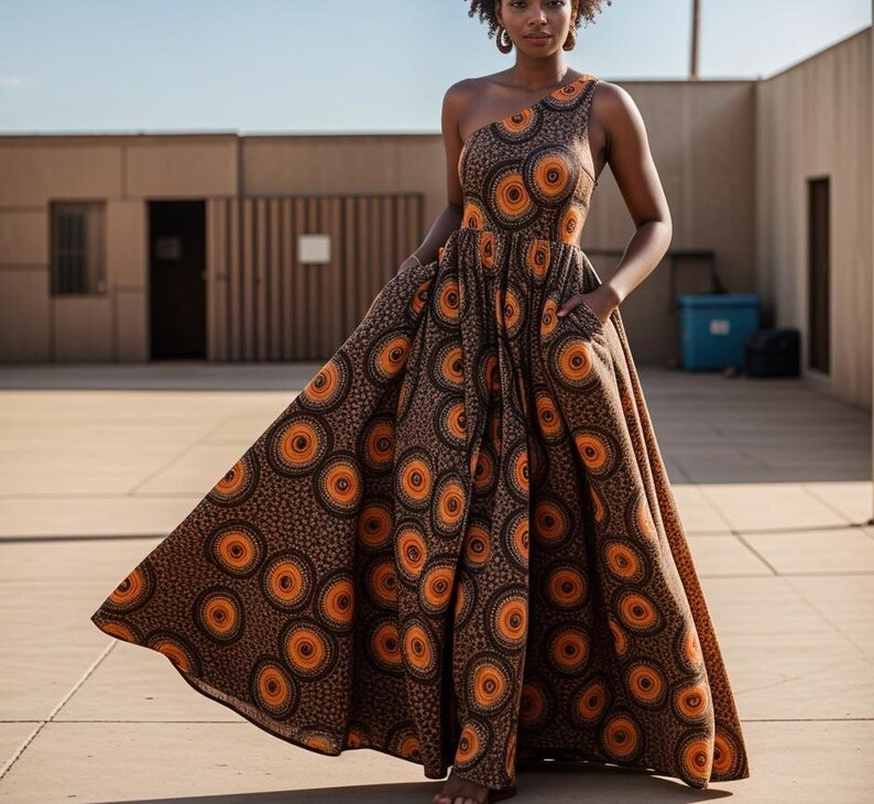 May include: A brown maxi dress with a one-shoulder neckline and a colorful geometric print featuring orange and black circles.