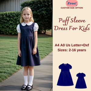 May include: A girl wearing a navy blue dress with white puff sleeves and a white Peter Pan collar. The dress has a gathered skirt and is knee-length. The girl is standing on a sidewalk with green grass in the background. The image also includes a text overlay that says "Free! Custom Size Option" and "Puff Sleeve Dress For Kids" in a red font. The text also says "A4 A0 Us Letter+Dxf Sizes: 2-16 years" in a brown font.