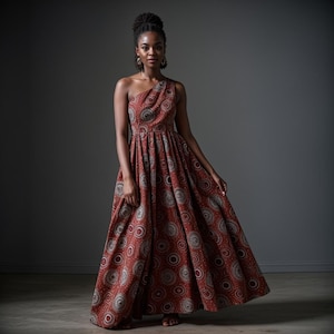 May include: A one-shoulder maxi dress with a rust-colored background and a pattern of white and gray circles. The dress has a fitted bodice and a flowing skirt.