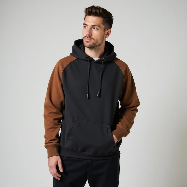 May include: A black hooded sweatshirt with brown sleeves. The sweatshirt has a kangaroo pocket and a drawstring hood.