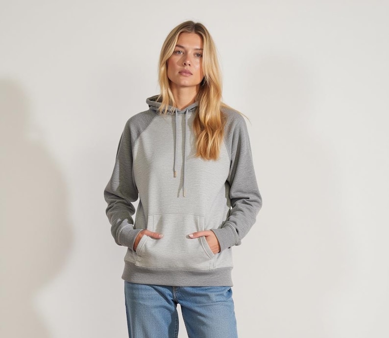 May include: A gray hooded sweatshirt with a contrasting gray and white color block design. The sweatshirt has a kangaroo pocket and a drawstring hood.