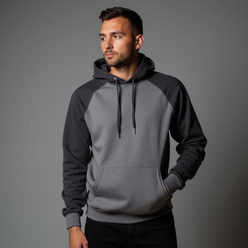 May include: A gray and black hooded sweatshirt with a contrasting color design. The sweatshirt has a kangaroo pocket and a drawstring hood.