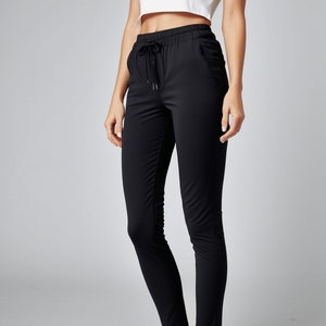 以下が含まれることがあります： フィットしたシルエットのブラックの紐付きパンツ。パンツはハイウエストで、レッグラインはゆったりとしたフィット感です。