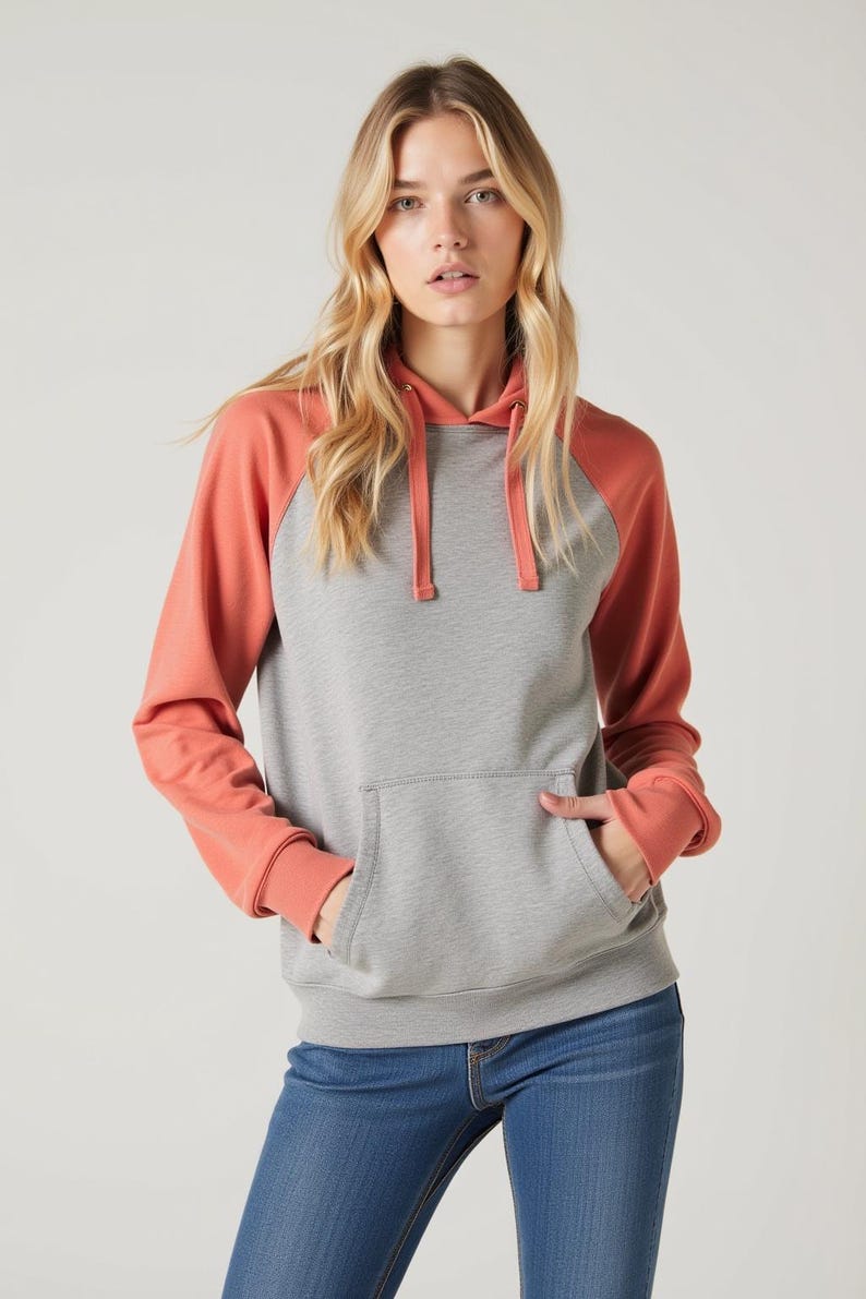 May include: A gray and coral colored hooded sweatshirt with a kangaroo pocket. The sweatshirt has a contrasting color on the sleeves and a drawstring hood.