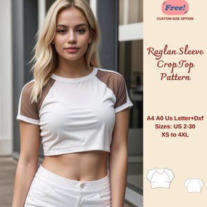 Op de afbeelding: Een wit crop top naaipatroon met raglanmouwen. Het patroon omvat maten US 2-30, XS tot 4XL. Het patroon is beschikbaar in A4, A0 en US Letter formaten in PDF en DXF. "Free! Custom Size Option" staat in rood bovenaan de afbeelding.