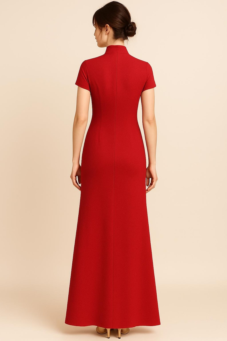May include: A floor-length, red dress with a high neckline and short sleeves. The dress has a fitted bodice and a flared skirt. The back of the dress is visible, showing a vertical seam. The model is wearing the dress.
