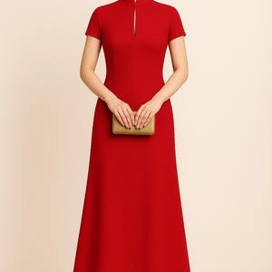 May include: A vibrant red, floor-length dress with short sleeves and a mandarin collar. The dress features a front slit and is paired with a small, gold clutch. The dress is a formal style, suitable for special occasions.