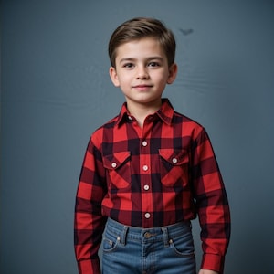 May include: A young boy wearing a red and black plaid button-down shirt and blue jeans. He is looking directly at the camera.