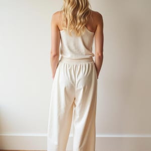 Puede incluir: Un top blanco sin mangas y pantalones anchos a juego hechos de una tela suave y c&oacute;moda. El atuendo es perfecto para relajarse en casa o hacer recados.