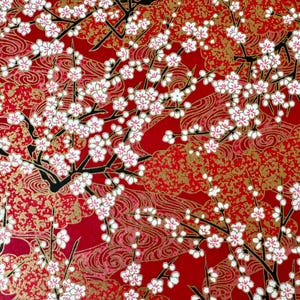 May include: A vibrant red background with a repeating pattern of white cherry blossoms on black branches. The design includes gold accents and swirling patterns, creating a rich, textured look. This image is ideal for decorative paper or fabric.