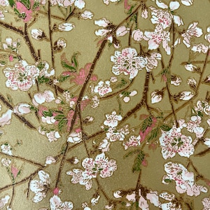 Può includere: Uno sfondo dorato con un motivo ripetitivo di fiori rosa e bianchi con foglie verdi. I fiori sono stilizzati e assomigliano ai fiori di ciliegio.