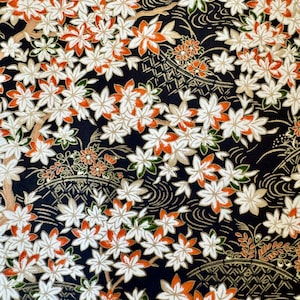 May include: Black fabric with a repeating pattern of white and orange flowers. The flowers are stylised and have a delicate, almost watercolour-like appearance. The background is a deep black, creating a striking contrast with the flowers.