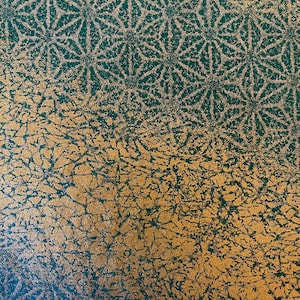 May include: Close-up of a textured surface with a two-tone design. The top half features a repeating pattern of gold-coloured star-like shapes on a dark teal background. The bottom half has a gold-coloured, crackled texture.