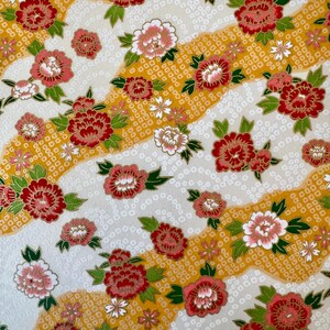 May include: A floral pattern featuring red, pink, and white flowers with green leaves on a cream-colored background. The design includes wavy yellow stripes with a dotted texture, creating a vibrant and detailed textile pattern.