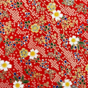 May include: Close-up of red patterned paper with a floral design. The paper features white flowers with yellow centres, blue berries, and gold accents. The background has a repeating white square pattern.