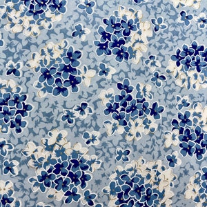 May include: A blue and white floral pattern on a light blue background. The flowers are arranged in clusters and have a gold outline.