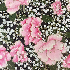 May include: A black background with a floral pattern featuring pink flowers with gold accents and white flowers with gold centers.