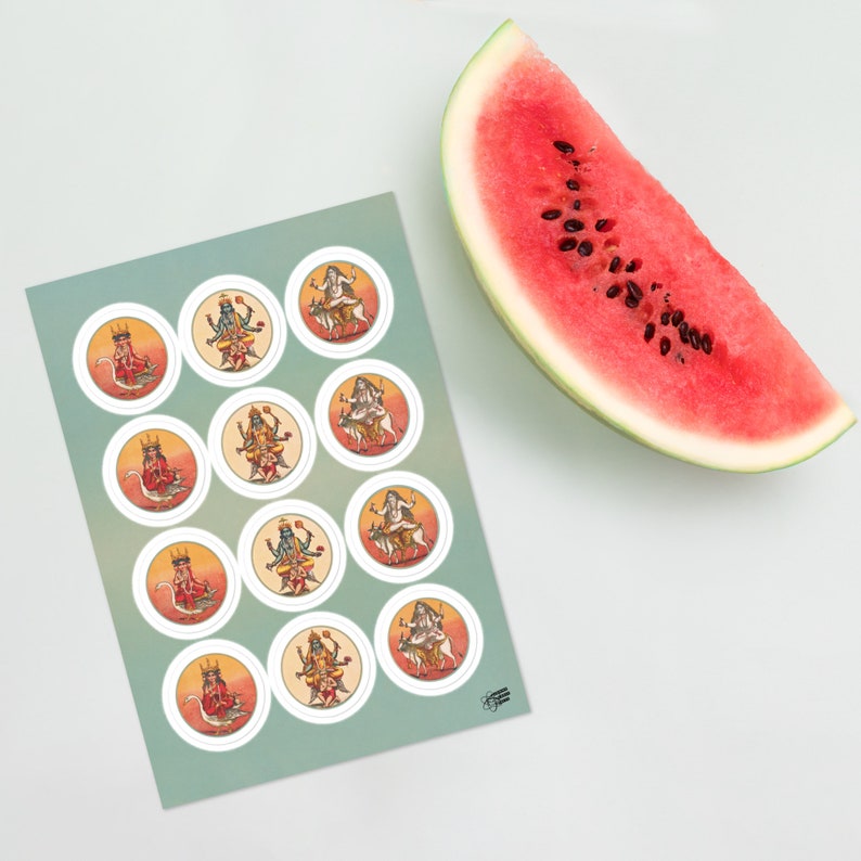 Op de afbeelding: Een vel ronde stickers met kleurrijke illustraties van hindoe&iuml;stische goden, met een plakje watermeloen op een wit oppervlak. De stickers hebben een witte rand en staan op een lichtgroene achtergrond.