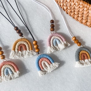 May include: Five rainbow-colored macrame necklaces with wooden beads. Each necklace features a different color combination of rainbow stripes.