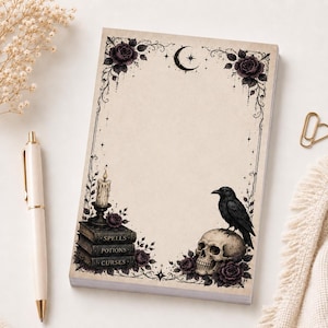 May include: A rectangular notepad with a cream-coloured background featuring a decorative border of dark roses, a crescent moon, and stars. The bottom left shows a stack of books labelled Spells, Potions, and Curses with a candle, and a skull with a raven.